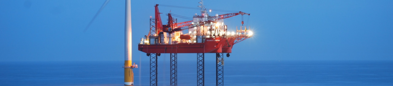 A photo of a jack-up barge next to a wind turbine